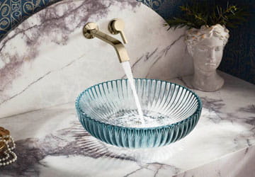 Plumbing Brass faucet filling a glass sink basin - Plumbing solutions from Facets of Charlotte NC