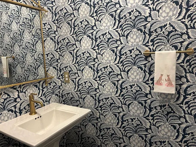 Bathroom sink with brass faucet in a bathroom with busy wallpaper